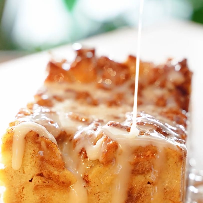 Sweet glaze drizzling over a warm, golden-brown bread pudding.